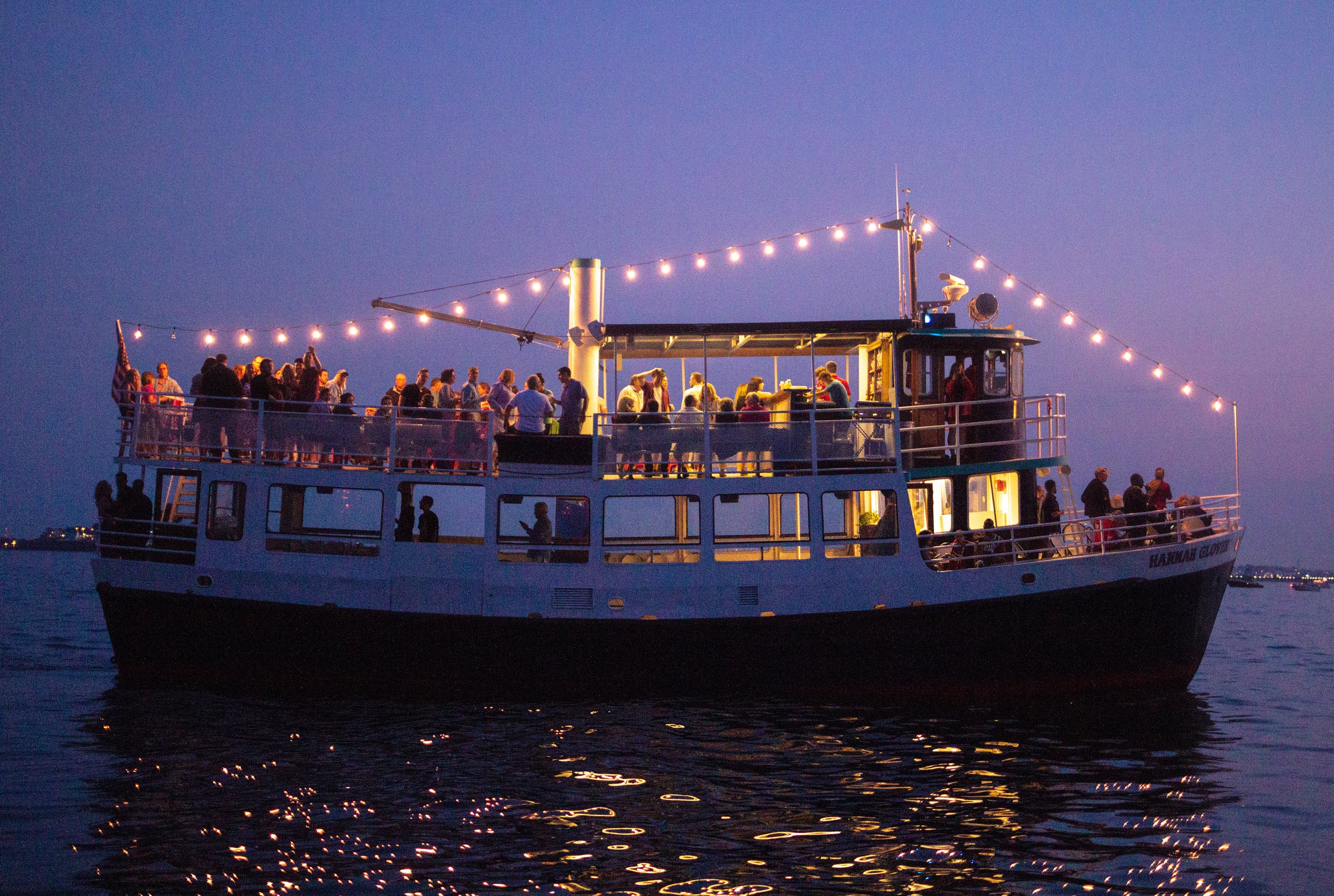 Gaze at the glittering lights of the city as light dances on the waters of boston harbor. Mahi Cruises